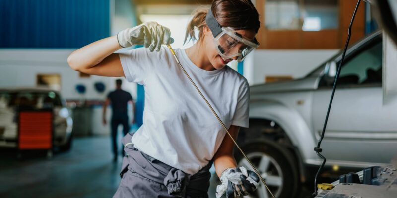 Eine junge Mechanikerin prüft das Motoröl eines Fahrzeugs in einer Werkstatt. (Foto: Antonio Suarez Vega (iStock))